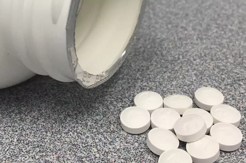 white circular pills next to bottle