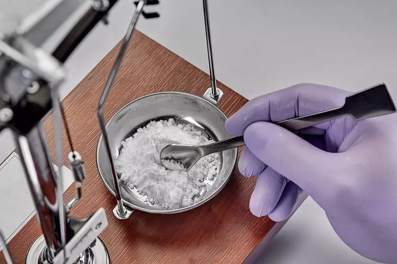 gloved hand mixing ingredients to make compounded medication