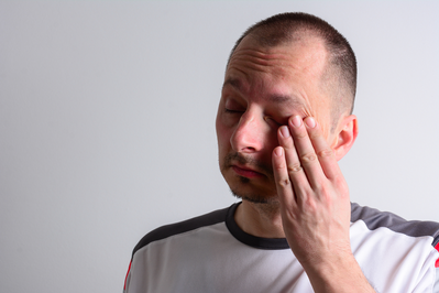 man rubbing eye with hand