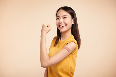 smiling woman showing off bandage on arm after receiving flu shot