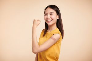 smiling young woman with bandage on arm after receiving immunization shot